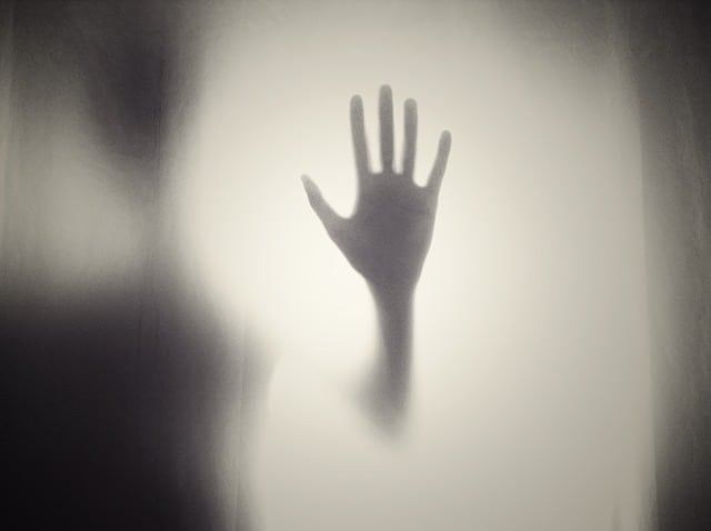 Mysterious shadow figure resting hand on foggy window